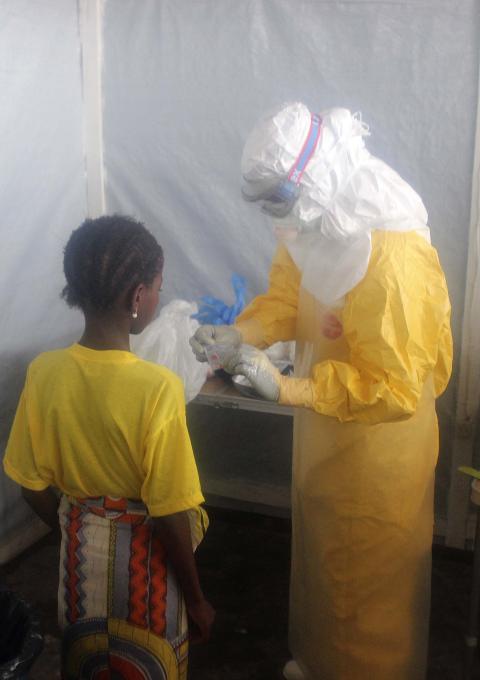 A nurse gives pain killers to a 12-years old girl staying in the Ebola isolation ward.